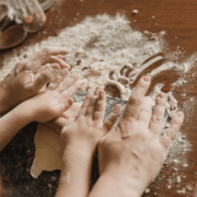 Hände im Mehl beim Ausrollen, große Hände unterstützen kleine Hände